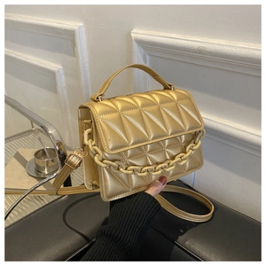 Detail of champagne gold square bag featuring quilted triangle pattern and metal chain
