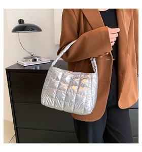 Detail of silver metallic quilted handbag with square embroidery and padded texture
