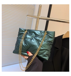 Detail einer grünen Stepptasche mit Metalleffekt und goldenen Kettenriemen