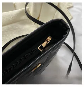 Detail of smooth gold zipper closure on black quilted leather handbag with diamond stitching