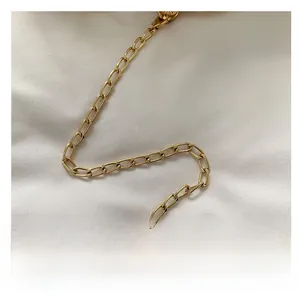 Close-up of a polished gold metal chain strap for a woven crossbody shoulder bag