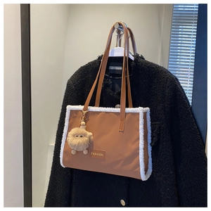 Détail d'un sac cabas en cuir marron avec bordure en fausse fourrure et plaque métal