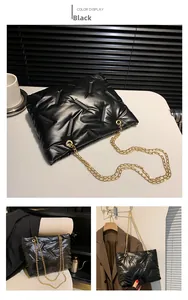 Detail der schwarzen gesteppten Puffer-Tasche mit Glanzeffekt und goldener Kette