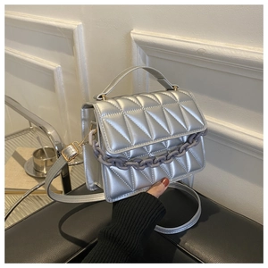 Detail of silver quilted crossbody bag featuring a thick grey-purple plastic chain decoration