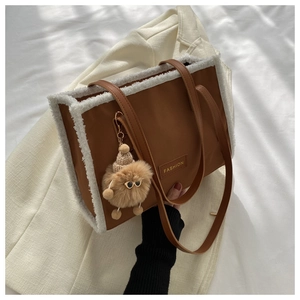 Détail du sac cabas avec bordure en fourrure et peluche sur fond de blazer blanc