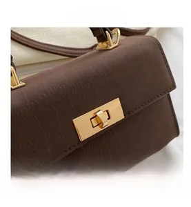 Dettaglio borsa in pelle goffrata marrone con chiusura girevole rettangolare dorata
