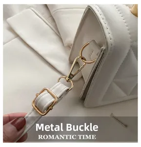 Detail of golden hardware clasp and strap buckle on white quilted crossbody bag