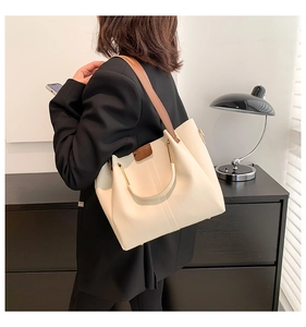 Side view of beige crossbody tote bag with brown straps and metal ring accent