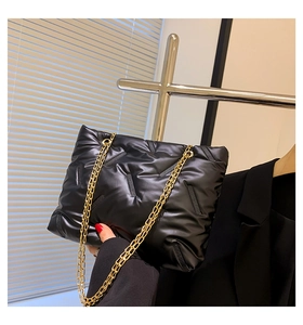 Detail der schwarzen gesteppten Puffertasche mit Hochglanz-Finish und Goldkette