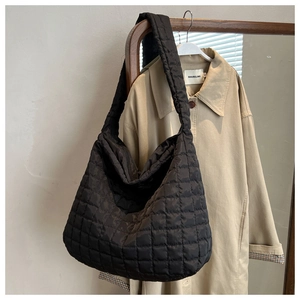 Detail of black quilted puffer tote bag fabric on khaki trench coat background