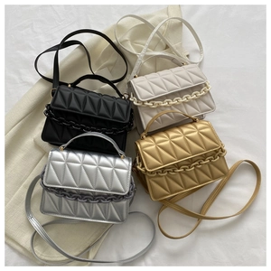 Flat lay of four quilted small square bags in black, white, silver and gold with chain detail