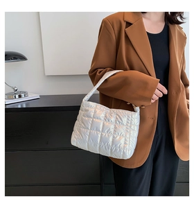 Close-up of silver quilted shoulder bag with shiny finish worn by a model in a suit