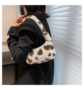 Detail of white plush shoulder bag with brown heart print shown on a model