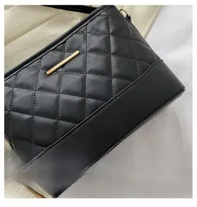 Close-up of black quilted crossbody bag showing precise stitching and golden metal bar