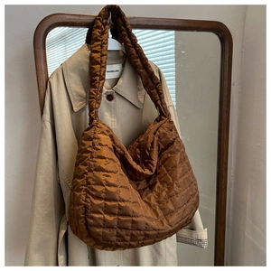 Detail of brown quilted nylon shoulder bag hanging on a mirror in a warm cozy setting