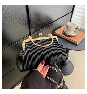 Details einer schwarzen Plissee-Clutch mit goldenem Herzschloss und abnehmbarer Kette