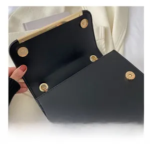 Gros plan du fermoir magnétique doré et des coutures sur un sac bandoulière en cuir noir