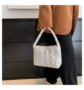 Detail of white quilted puffer handbag with metallic gloss and stitched square pattern