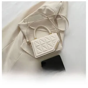Detailed view of beige quilted small crossbody bag with woven handle on a suit jacket