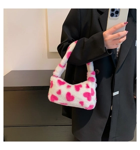Detail of soft white plush handbag with pink heart patterns and fuzzy texture