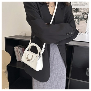 Detailed shot of a white mini PU leather trapezoid handbag with silver crescent buckle