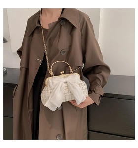 Detail of vintage tweed handbag with organza bow and golden handle on trench coat