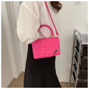 Detail of bright pink crossbody bag with geometric texture and woven handle on a model