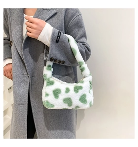 Detail of white plush underarm bag with green hearts on a model's grey coat