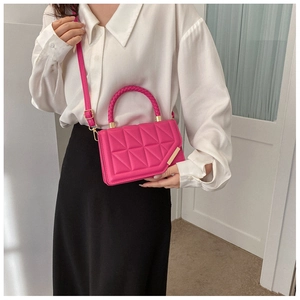 Detail of rose pink crossbody bag with triangular quilted pattern and woven handle