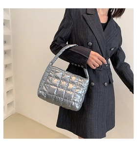 Close-up of metallic silver quilted tote bag with lattice stitching worn by a model
