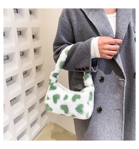 Detail of white plush handbag with green heart print and smooth metal zipper closure