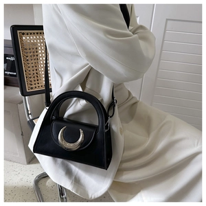 Detailed close-up of a black leather handbag featuring a large silver crescent moon buckle