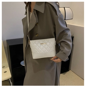 Close-up of white quilted leather crossbody bag with gold metal hardware and fine stitching