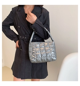 Close-up of a silver quilted puffer tote bag with metallic finish and wide handle