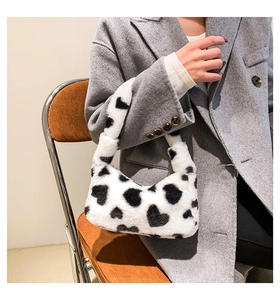 Close-up of fluffy black and white heart pattern faux fur handbag held by model