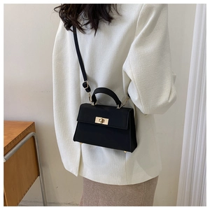 Dettaglio della borsa trapezoidale in pelle nera opaca con chiusura a scatto dorata