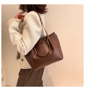 Brown faux leather tote bag showing spacious design and vertical stitching on shoulder strap