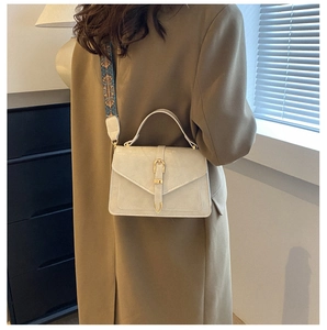 Detail of cream crossbody bag with gold clasp and ethnic style patterned strap