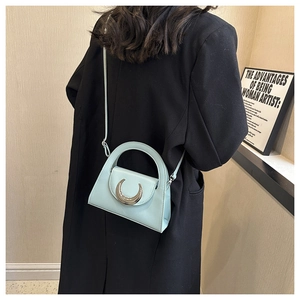 Detail of light blue crossbody bag with silver crescent buckle on black blazer