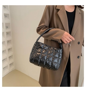 Close-up of quilted black down handbag featuring glossy nylon fabric and padded top handle