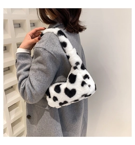 Detail of plush faux fur shoulder bag with black and white cow print and heart patterns