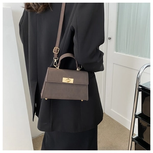 Brown crocodile embossed small square bag styled on a black blazer with golden buckle detail