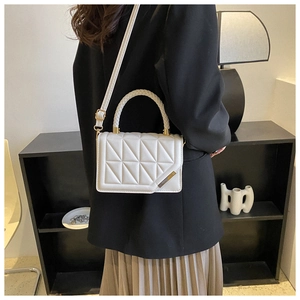 White geometric quilted crossbody bag styled on a model in a modern home setting