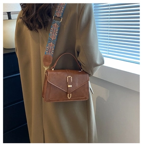Close-up of a brown vintage satchel with gold hardware and geometric pattern strap