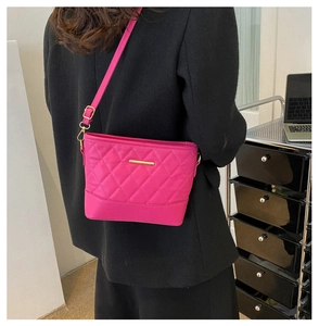 Detail of a rose red quilted crossbody bag featuring elegant gold hardware and strap