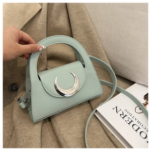 Detail of mint green mini handbag featuring a large silver crescent metal buckle