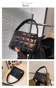 Detail of black quilted puffer tote bag with square embroidery and glossy finish