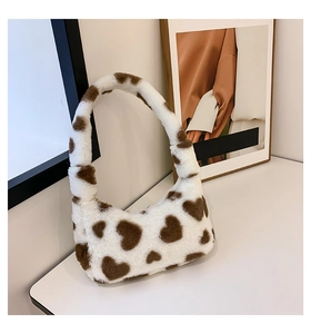 Close-up of heart pattern faux fur handbag on white surface with artistic background
