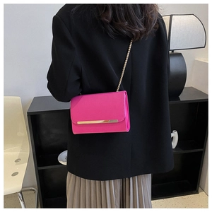 Vista lateral de un bolso bandolera rosa fucsia con cadena dorada usado por una modelo