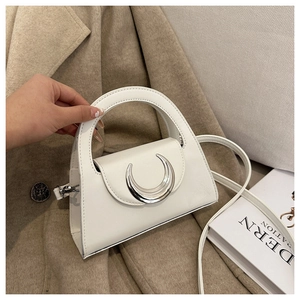 Detailed close-up of white mini handbag with silver crescent buckle on a wool coat